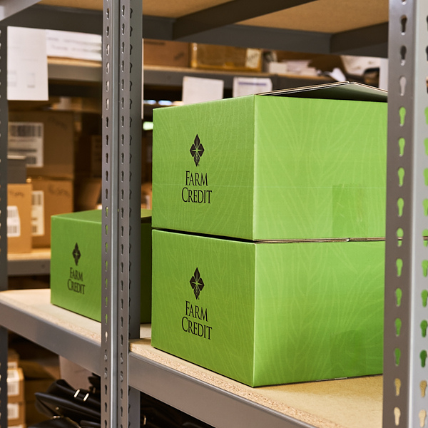 Green branded Farm Credit boxes organized on a shelf, ready for shipment
